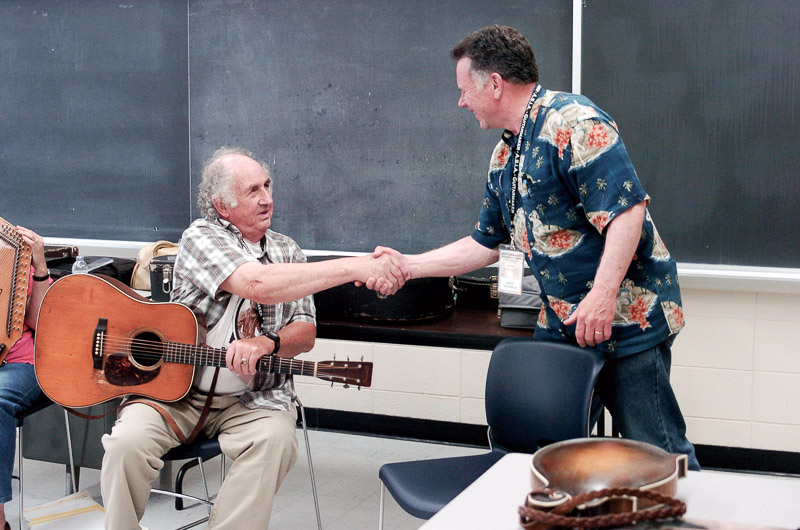 two men shake hands before playing music together